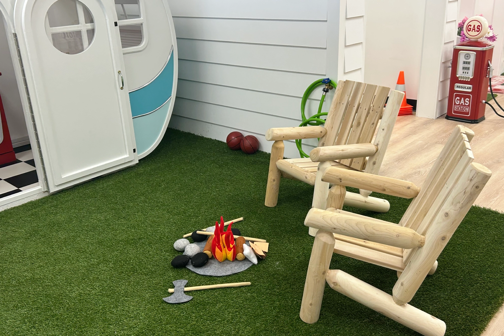 A cozy indoor campfire setup with wooden chairs and a toy camper.