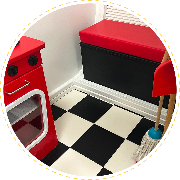 Small play kitchen setup with red appliances and black-and-white checkered floor.